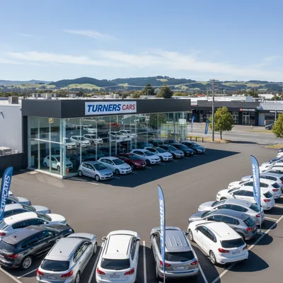 The storefront of Turners Cars Dunedin, a large used car dealership on Anzac Avenue, showing the main entrance and rows of vehicles for sale on the lot.